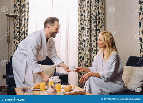 Happy Mature Couple In Bathrobes Smiling Each Other While Having