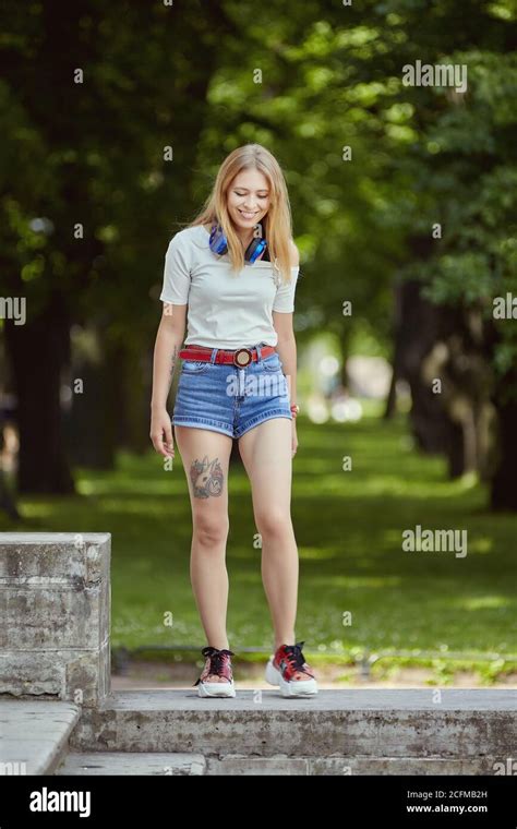 smiling russian woman in denim shorts has a rest in the public park at