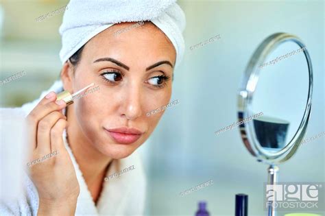 Beautiful Woman Applying Beauty Serum While Looking In Mirror At Home
