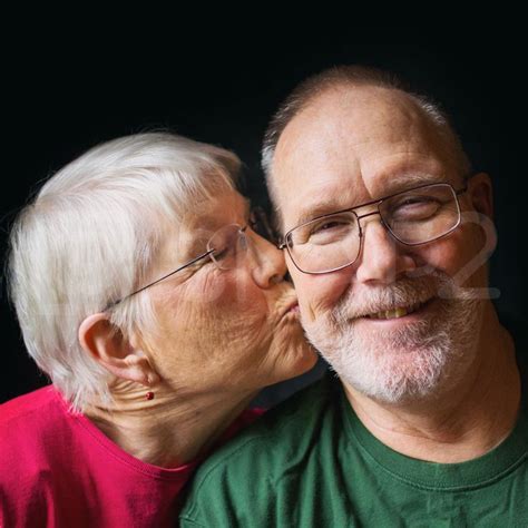 An Older Couple Kissing Each Other With Their Eyes Close To The Camera
