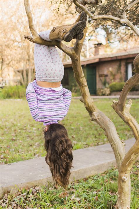 rear view of girl hanging upside down on her leg over the