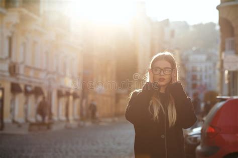 outdoor portrait of stylish blonde girl with red lips wearing glasses