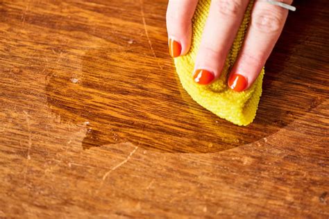 womans hand  red nails polishing  wooden surface  holding  yellow cloth