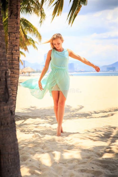 Blonde Girl In Azure With Hands On Breast Near Palms On Beach Stock