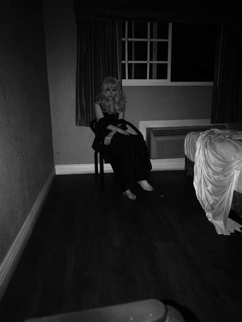 A Woman Sitting On A Chair In A Dark Room