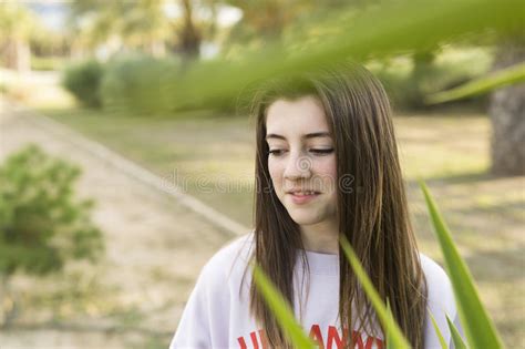 16 Year Old Teenager Sitting In A Park With Grass And Flowers Stock