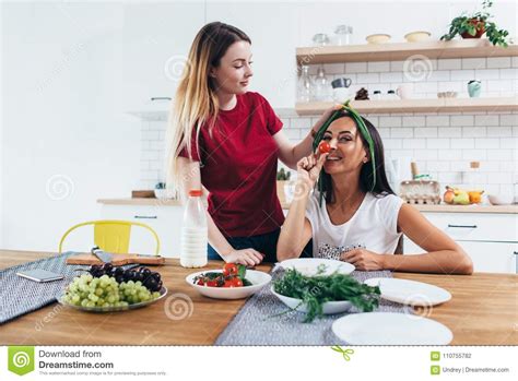 girls fooling around in the kitchen playing with vegetables stock