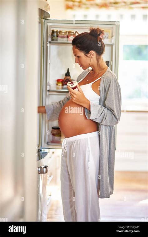 Pregnancy Cravings A Pregnant Woman Standing In Front Of A Fridge With