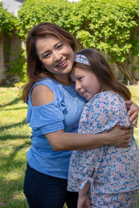 Latina Mother And Daughter Smiling And Laughing Outside In Back Yard