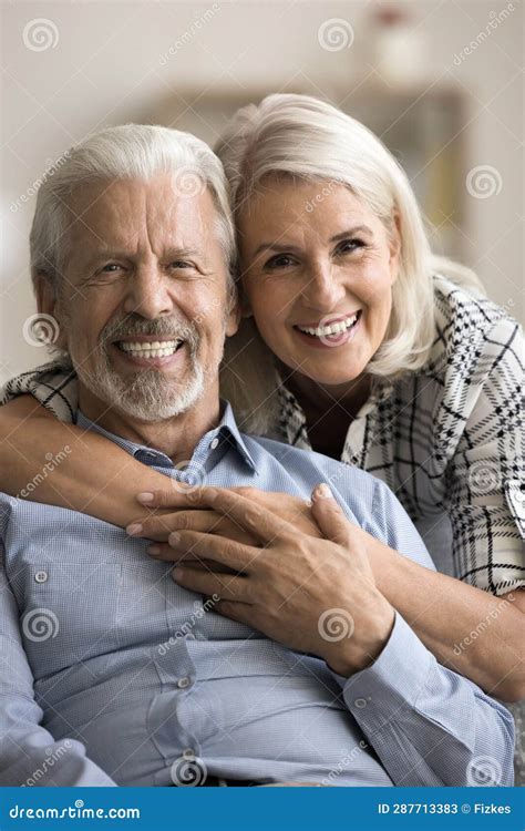 Happy Cheerful Mature Couple Hugging On Sofa For Home Portrait Stock