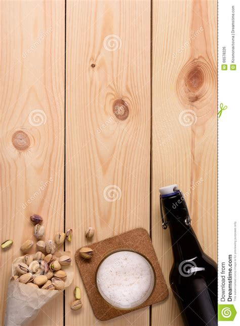 Glass Of Craft Beer Bottle And Pistachio Nuts On Wood