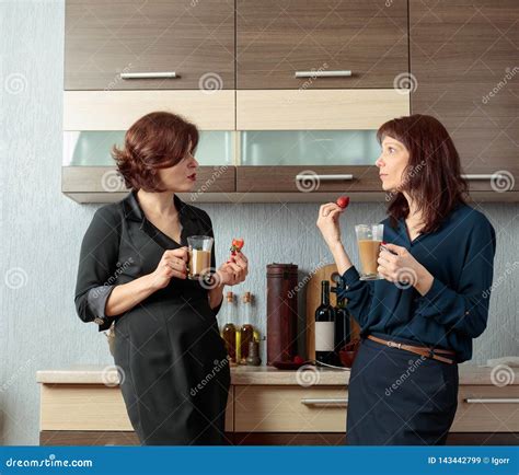 Two Girlfriends Talk And Drink Coffee In The Kitchen Stock Image
