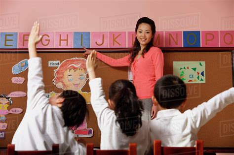teacher teaching alphabet  students raising hands  class stock photo dissolve