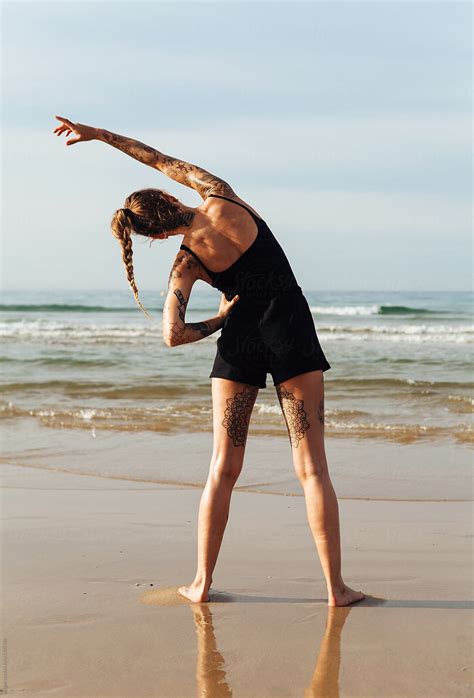 Woman Stretching On The Beach Facing The Sea With Her Back To The