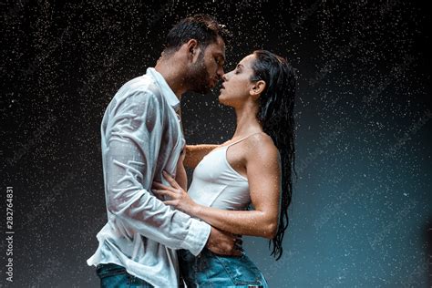 Side View Of Handsome Man Kissing Sexy Wet Girlfriend Under Raindrops