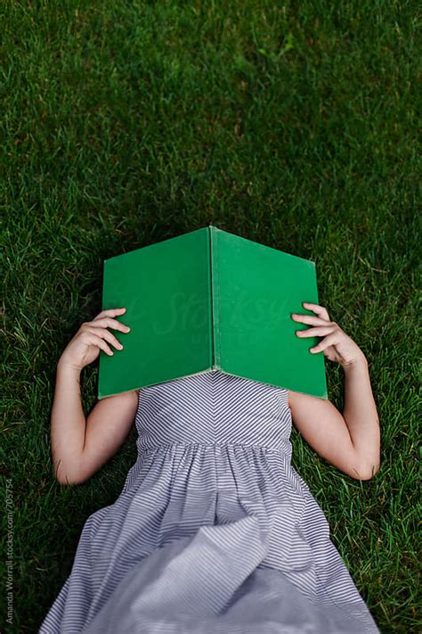 vertical shot of girl laying in grass with vintage book covering her