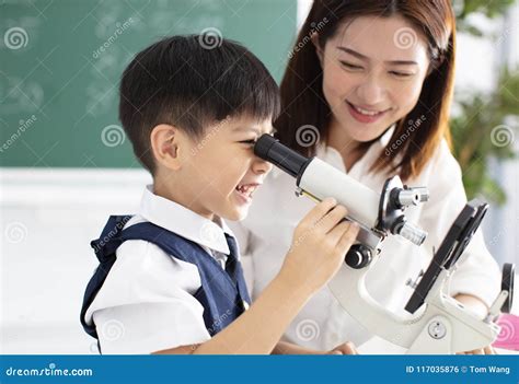 teacher helps child  conduct experiment  microscope stock photo