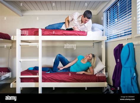 A Man And Woman Relax On Bunk Beds In An Adventure Lodge With Implied