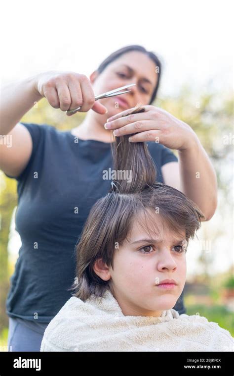 Mother Cuts Her Son S Hair In The Garden At Home The Mother Is A