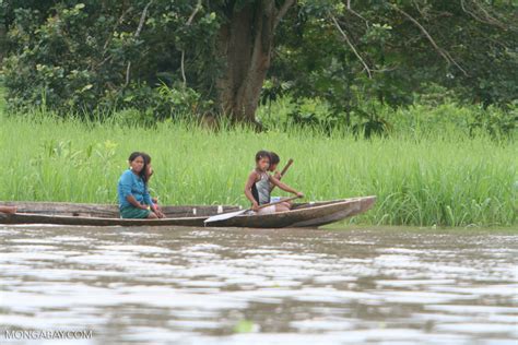 girls paddling a dugout canoe in the amazon
