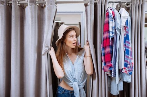 Premium Photo Surprised Young Woman Trying On Clothes And Looking Out