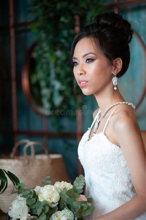 Asian Bride With Flowers In White Dress Sitting On Sofa Stock Image