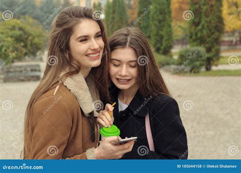 two girlfriends try to warm up with a hot drink in the outdoors stock