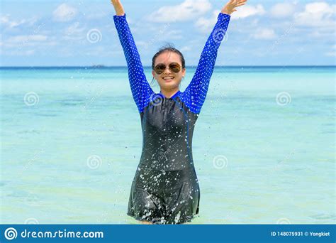 happy asian teen girl play splashing water in the sea