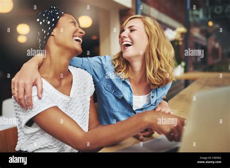 Two Affectionate Multiracial Women Friends Hugging And Laughing As They