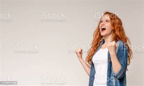 emotional redhead girl screaming yes and raising clenched fists stock
