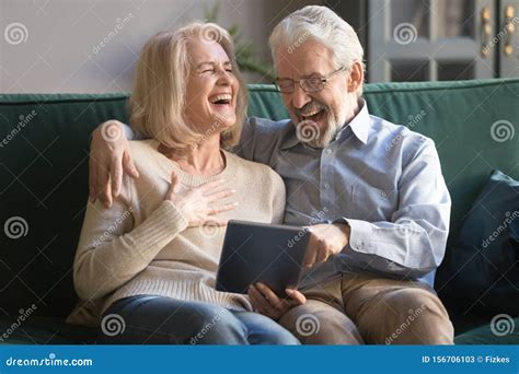 Cheerful Old Couple Laughing Using Digital Tablet At Home Stock Image