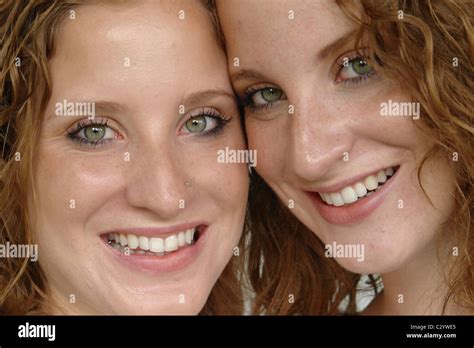 Closeup Portrait Of Twin Sisters Posing Cheek To Cheek And Smiling