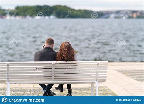 couple sitting on a bench overlooking water stock image