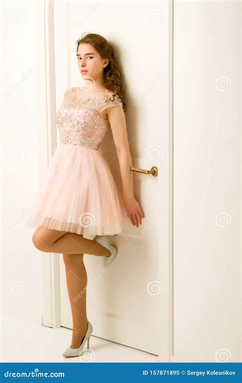 dziewczyna nastolatka w sprytnej sukience stojącej obok białych drzwi