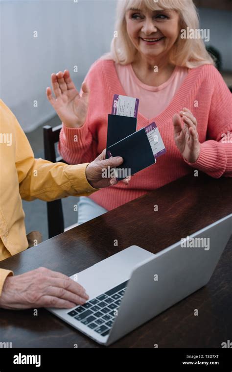 senior man holding air tickets and passports near surprised woman at