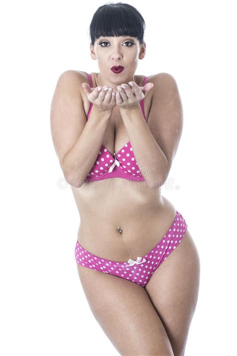 gorgeous cute glamorous pin up model posing in pink polka dot lingerie blowing kisses stock