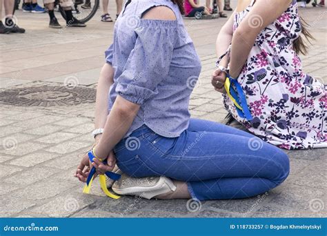 two women with their hands tied behind their backs sit on their stock