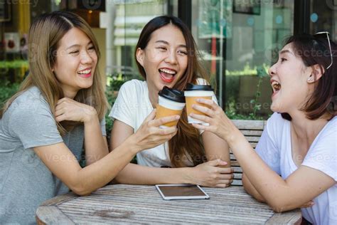 Cheerful Asian Young Women Sitting In Cafe Drinking Coffee With Friends