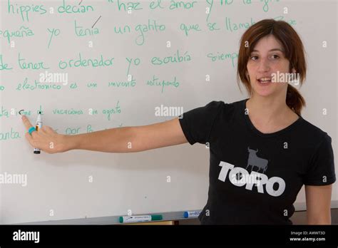 A Spanish Woman Teaching Spanish In A Classroom In Front Of Whiteboard