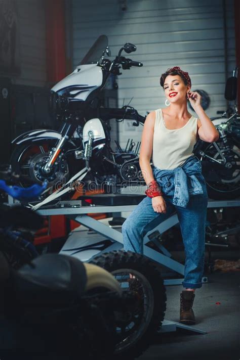 beautiful girl posing repairs a motorcycle in a workshop