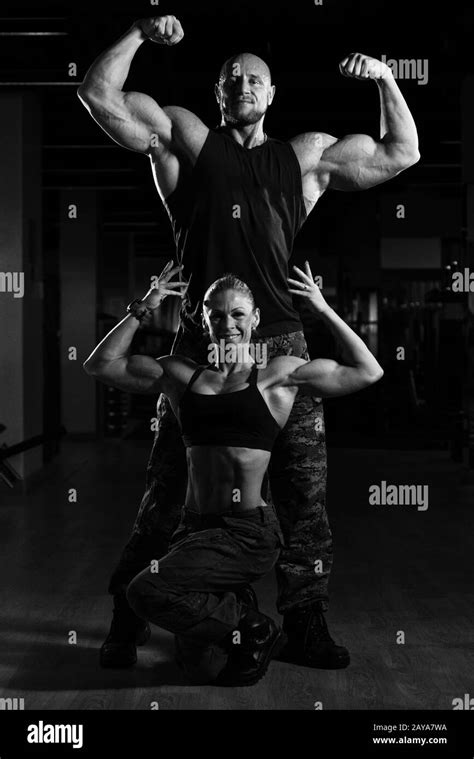 Fitness Couple Standing Strong In The Gym And Flexing Muscles