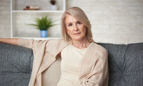 Beautiful Older Blonde Woman Is Sitting On A Sofa Stock Image Image