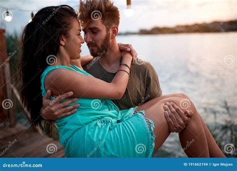 Beardy Man Holding In Arms Beautiful Woman By The Sea At Sunset