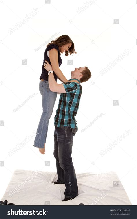 A Man Lifting Up His Woman In The Air On Their Bed Stock