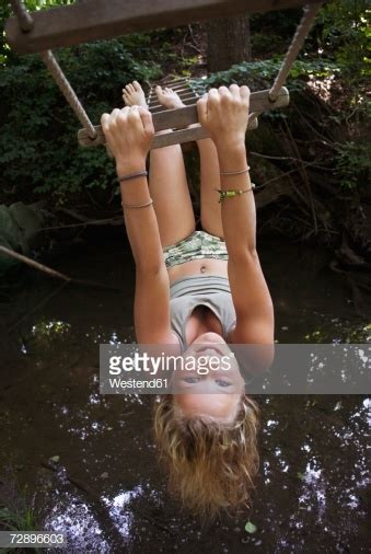 teenage girl hanging upside down on ropeladder closeup