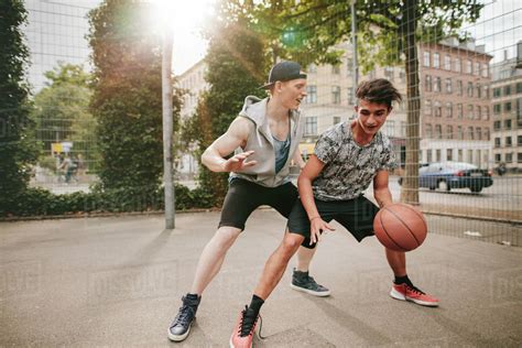 teenagers playing basketball  outdoor court   fun young man