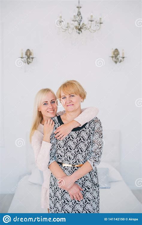 two beautiful women a mother and daughter standing in white bedroom