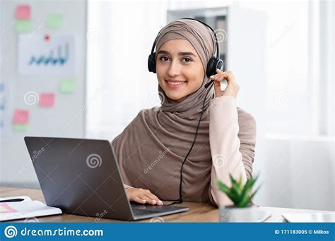 beautiful arabic woman in hijab wearing headset working in modern