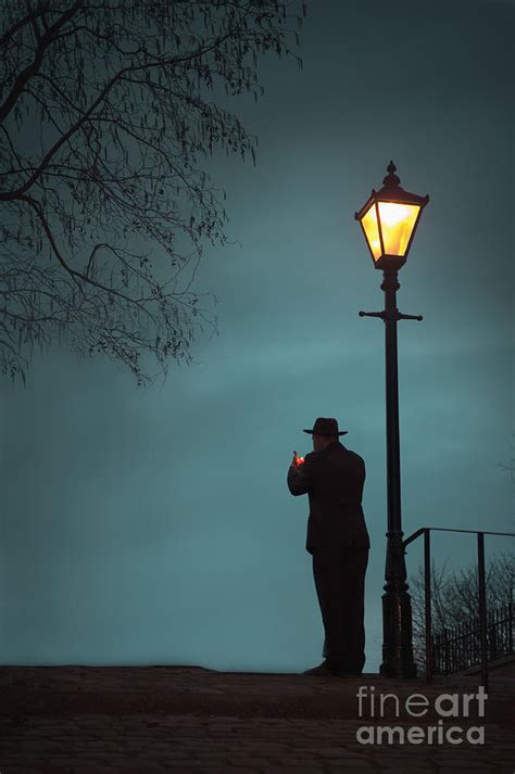 man lighting  cigarette beneath  illuminated street light photograph  lee avison fine art
