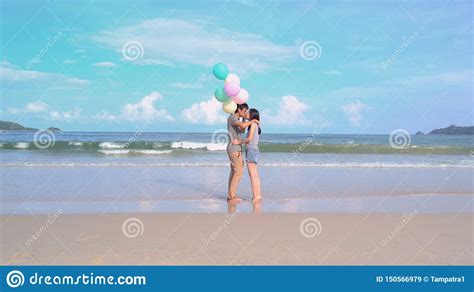 happy asian couple kissing holding colorful balloons at